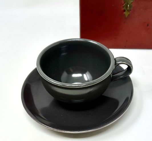 Black ceramic cup and saucer set on a white background
