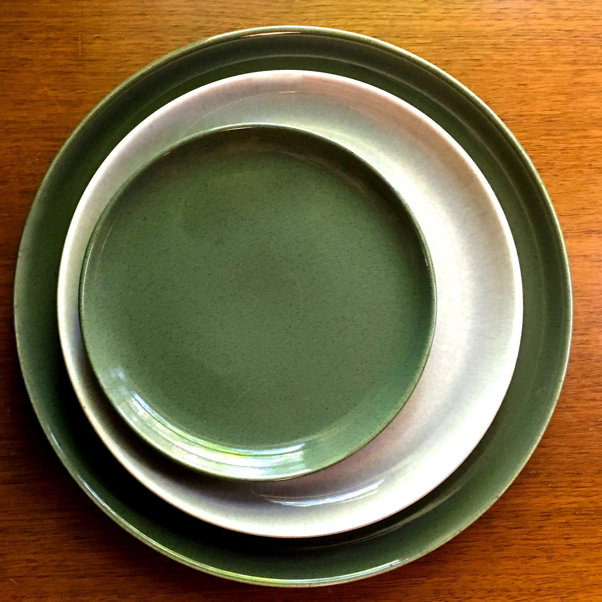 Stack of green ceramic plates on a wooden surface