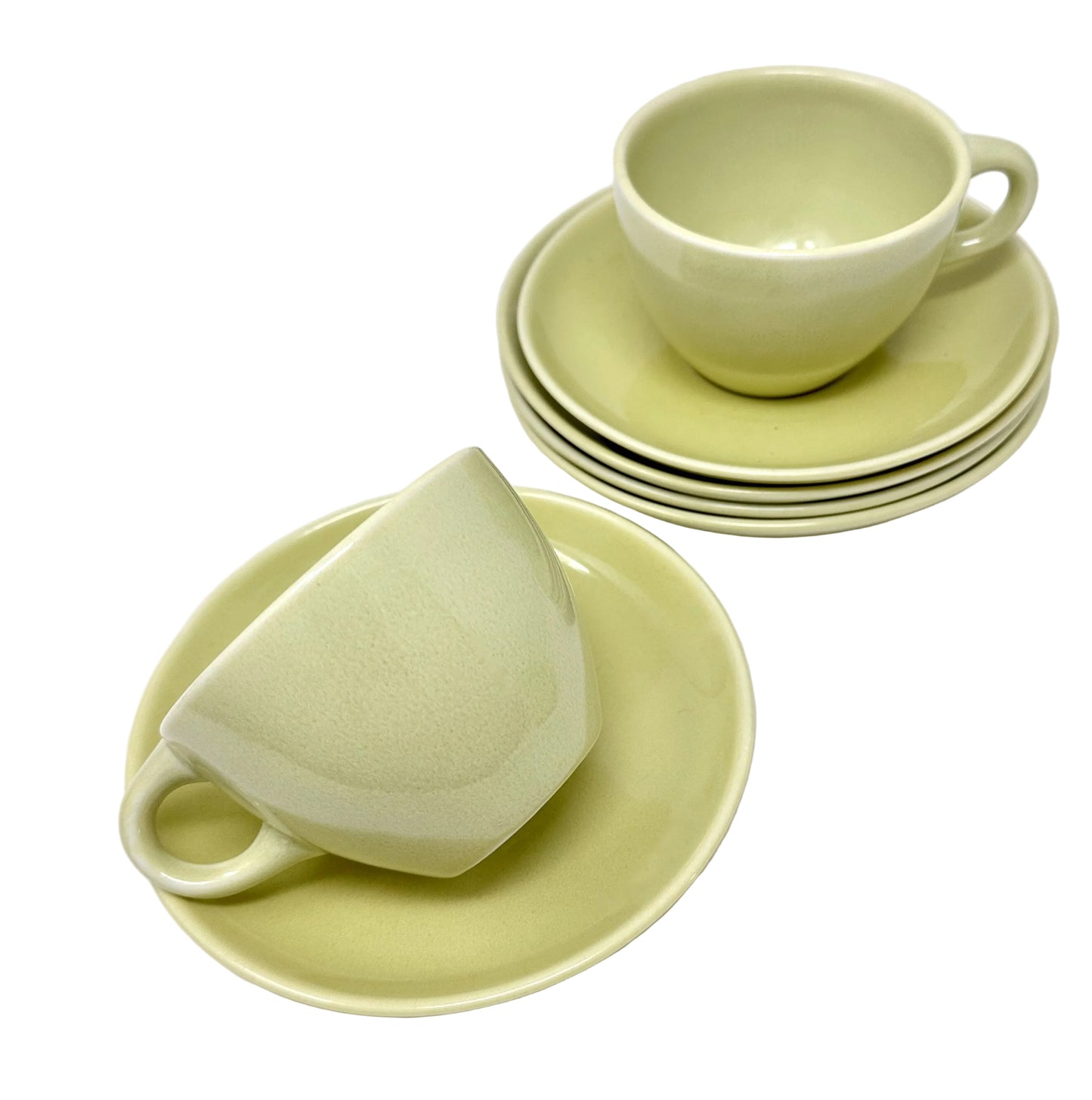 Set of light green ceramic cups and saucers on a white background