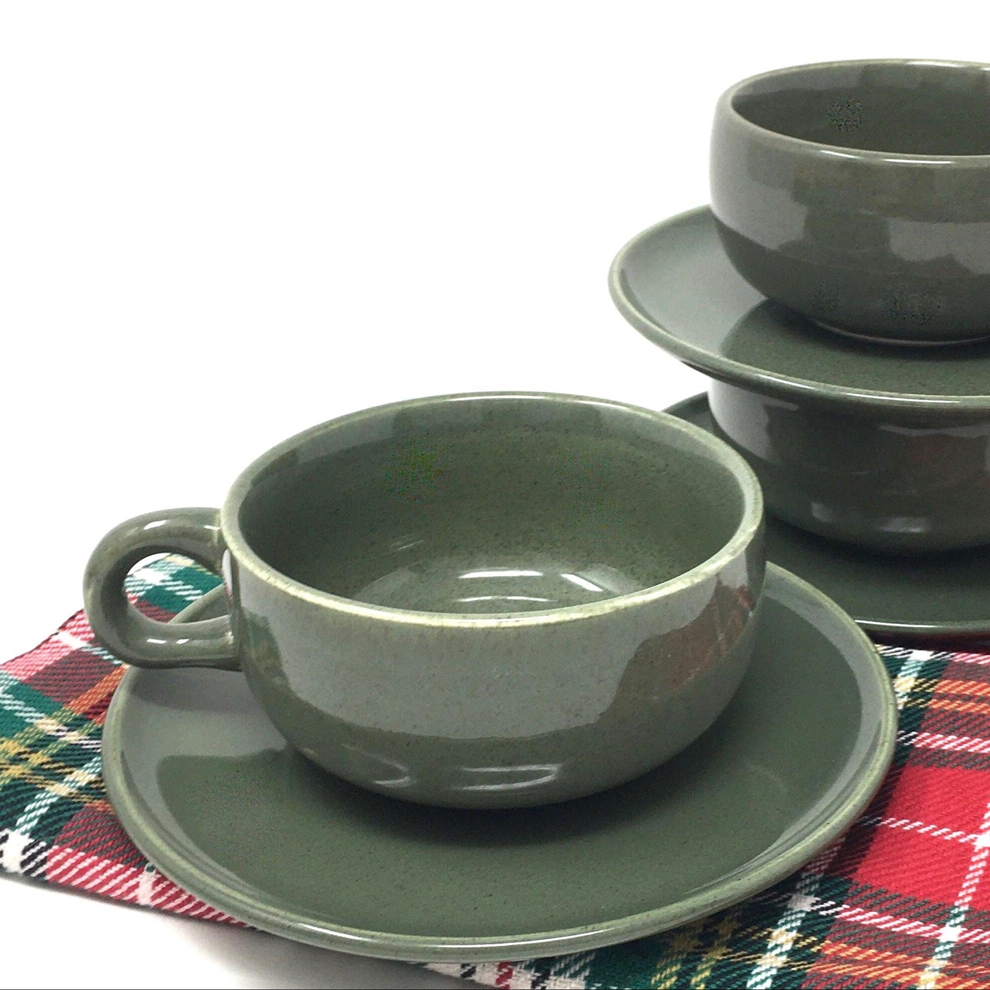 Set of green ceramic cups and saucers on a plaid tablecloth