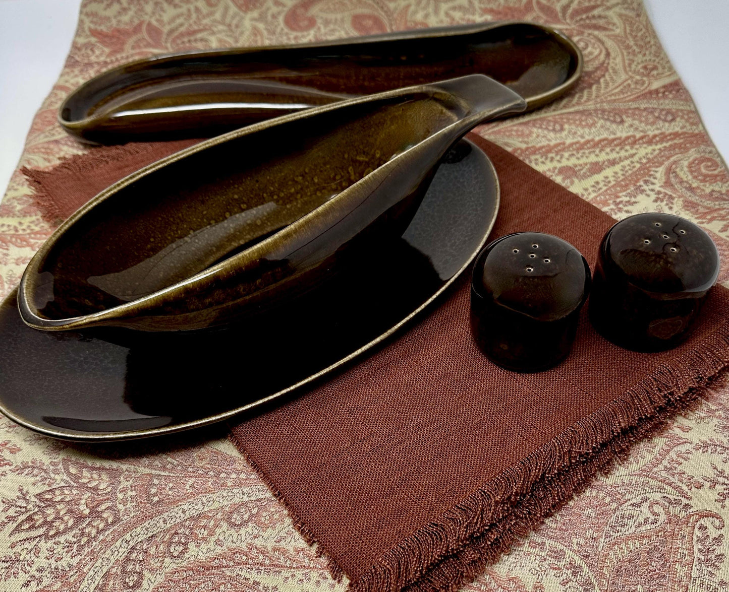 Set of black ceramic serving dishes on a patterned fabric surface