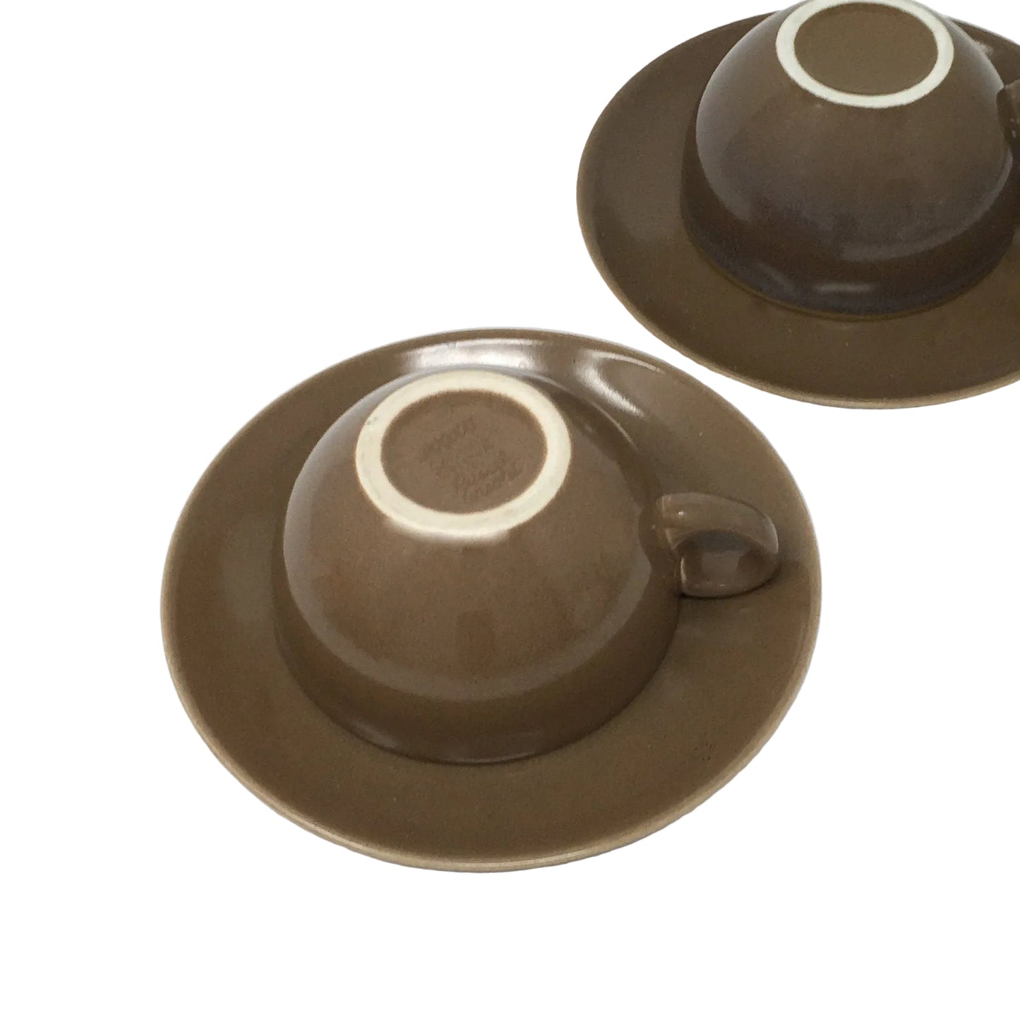 Two brown ceramic cups with saucers on a white background